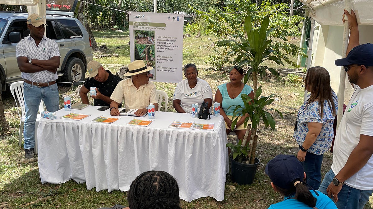 Cacao farmers sitting at a table talking to an audience