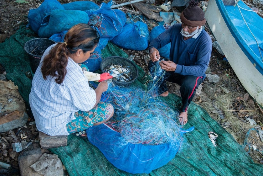 Man and woman mend a fishing net