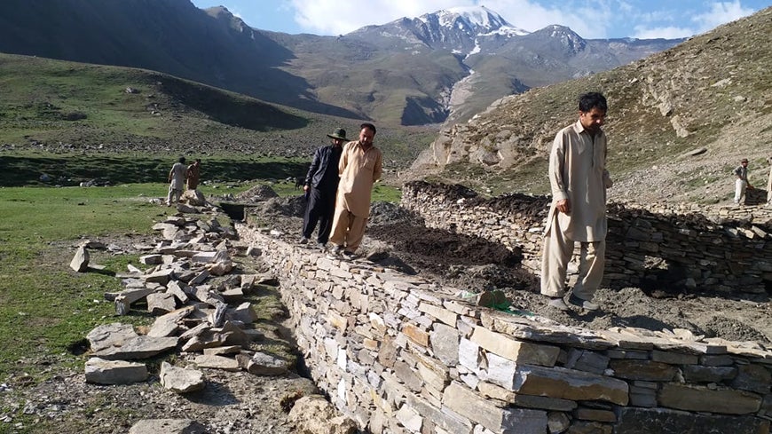 Villagers walking along predator-proof livestock corral in Pakistan