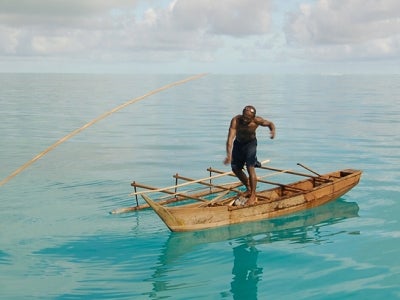 Spear fisher on a small boat in open sea