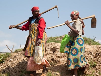 Two Rwandan women with farming tools
