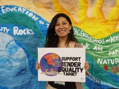 Woman holding sign behind colorful background