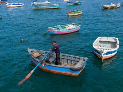 Fisherman in small boat going close to shore