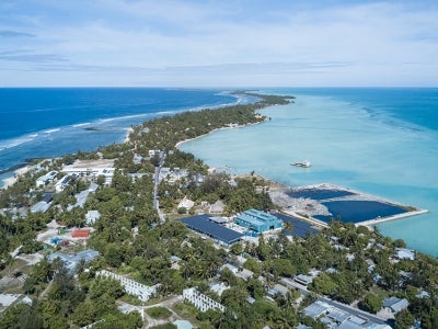 Tarawa atoll of Kiribati; green island peninsula with buildings and blue ocean waters