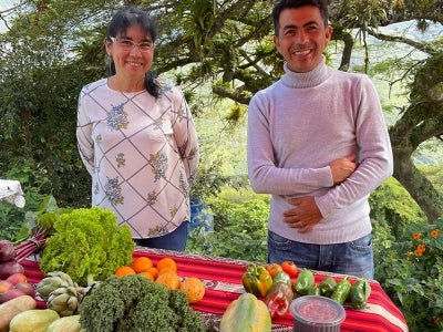 Man and woman stand in front of vegetables on a table
