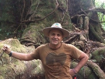 Man wearing a hat standing in front of a large tree