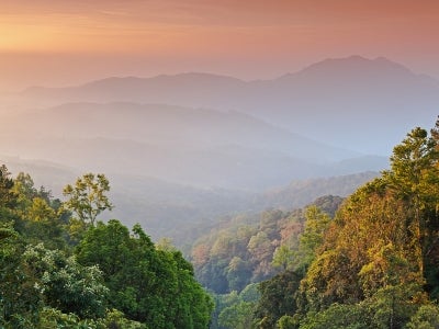 Sunrise over a forest-covered mountain landscape in Thailand