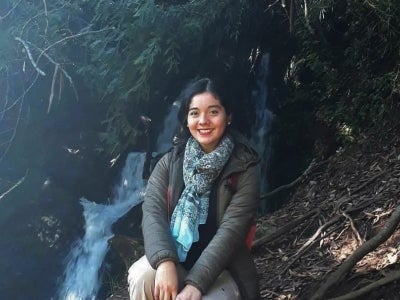 Girl sitting in front of a small waterfall