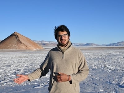 Man standing on a snow-covered landscape with mountains in background