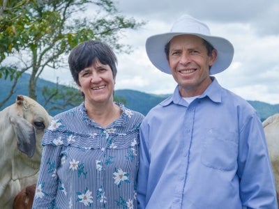 Portrait of man and woman with cows and mountain landscape in background