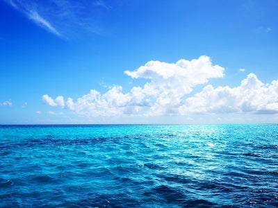Open blue ocean and partially cloudy sky with sun