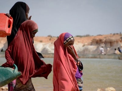 Women gathering water near sand dam