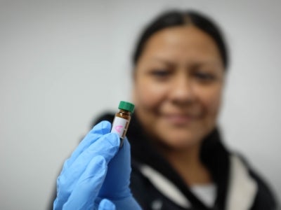 Woman holds up a small vial for the camera