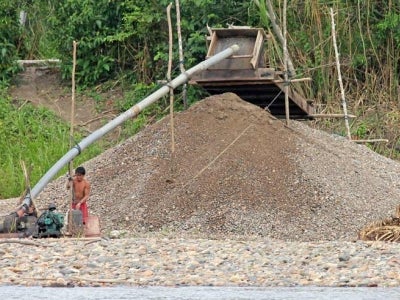 Small-scale gold miner next to tailings pile in Peru