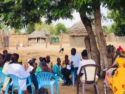 Women gathering under a tree near a village in South Sudan.