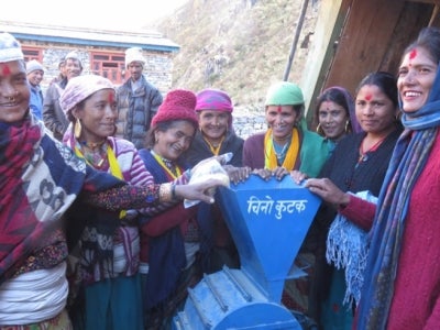 Nepalese women stand around a millet machine