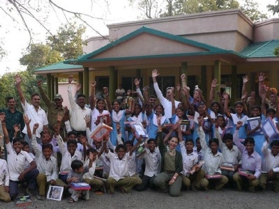 Students and teachers in a group photo with hands raised