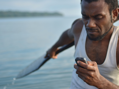 Man with paddle in hand checking cell phone