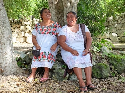 Mexican women rest against a tree