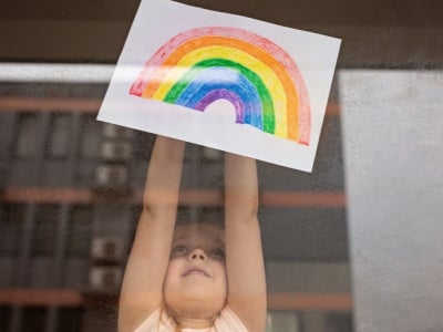 Girl displays her painting of a rainbow in the window