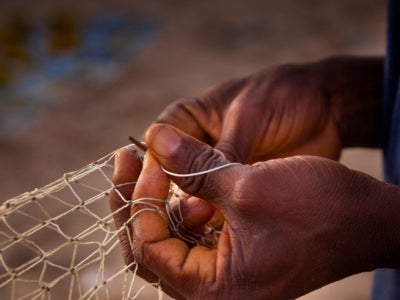 A person tying a fishing net in Sierra Leone