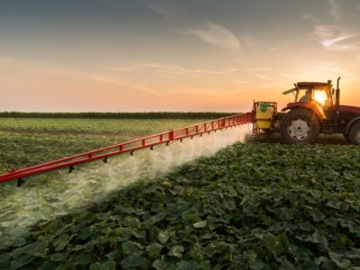 Tractor spraying pesticides on vegetable field with sprayer at spring. Photo: Fotokostic/Shutterstock.
