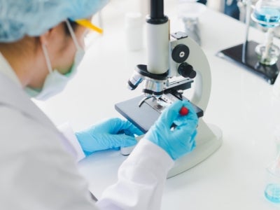 Woman using a microscope. Photo: Tong Nawarit/Shutterstock.