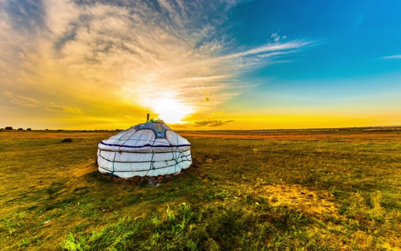 Yurt in the Mongolian steppe with sun and colorful sky