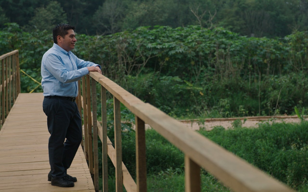 Man standing on wooden bridge overlooking landscape