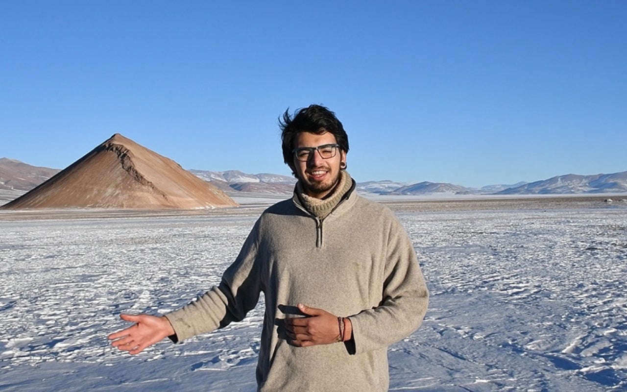Man standing on a snow-covered landscape with mountains in background