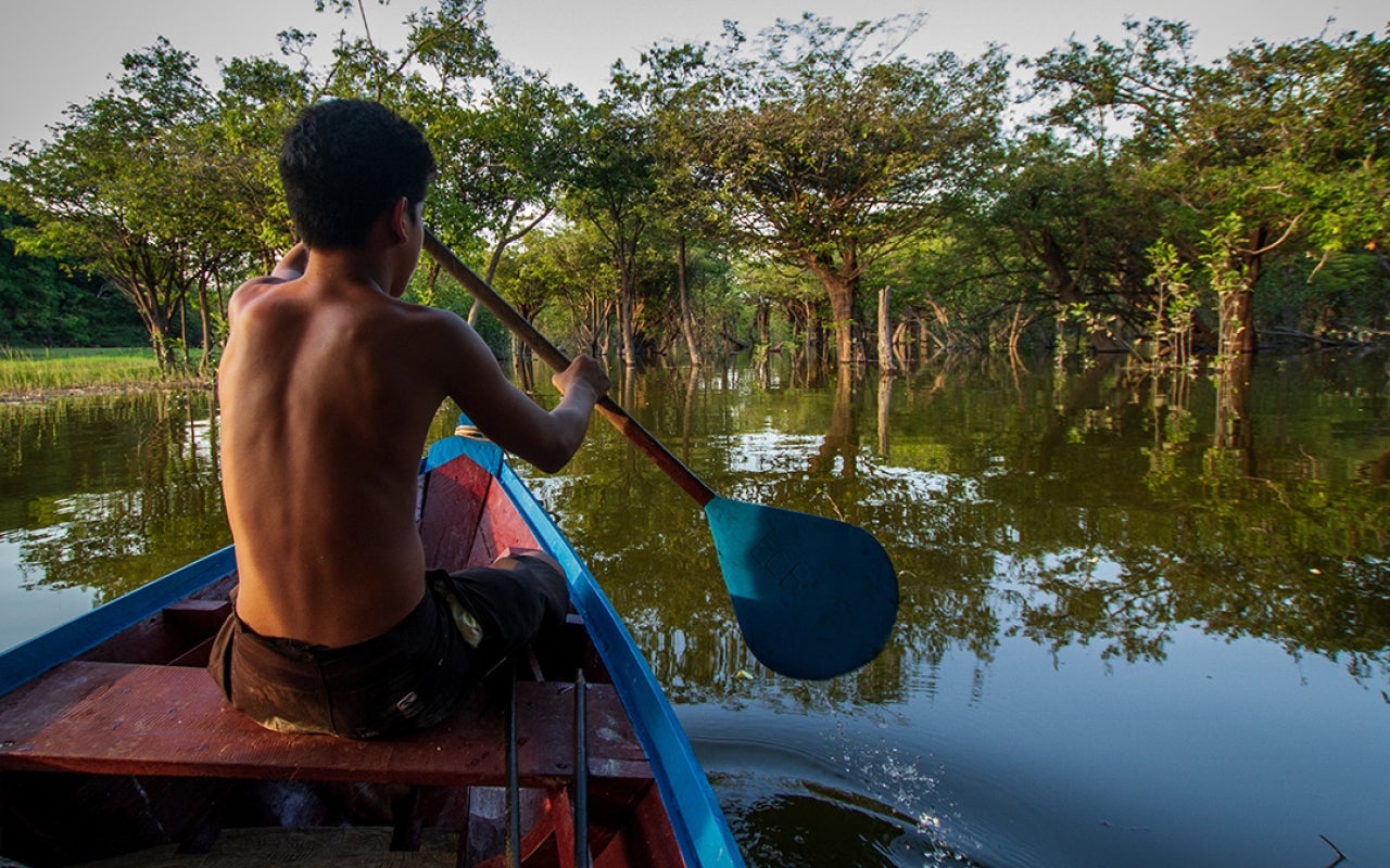 Boy on boat with paddle through Indigenous territory and protected area on the Tapajós River, Amazon - Brazil