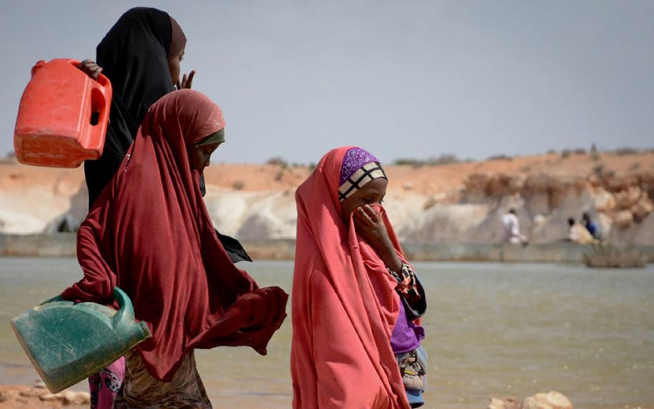 Women gathering water near sand dam