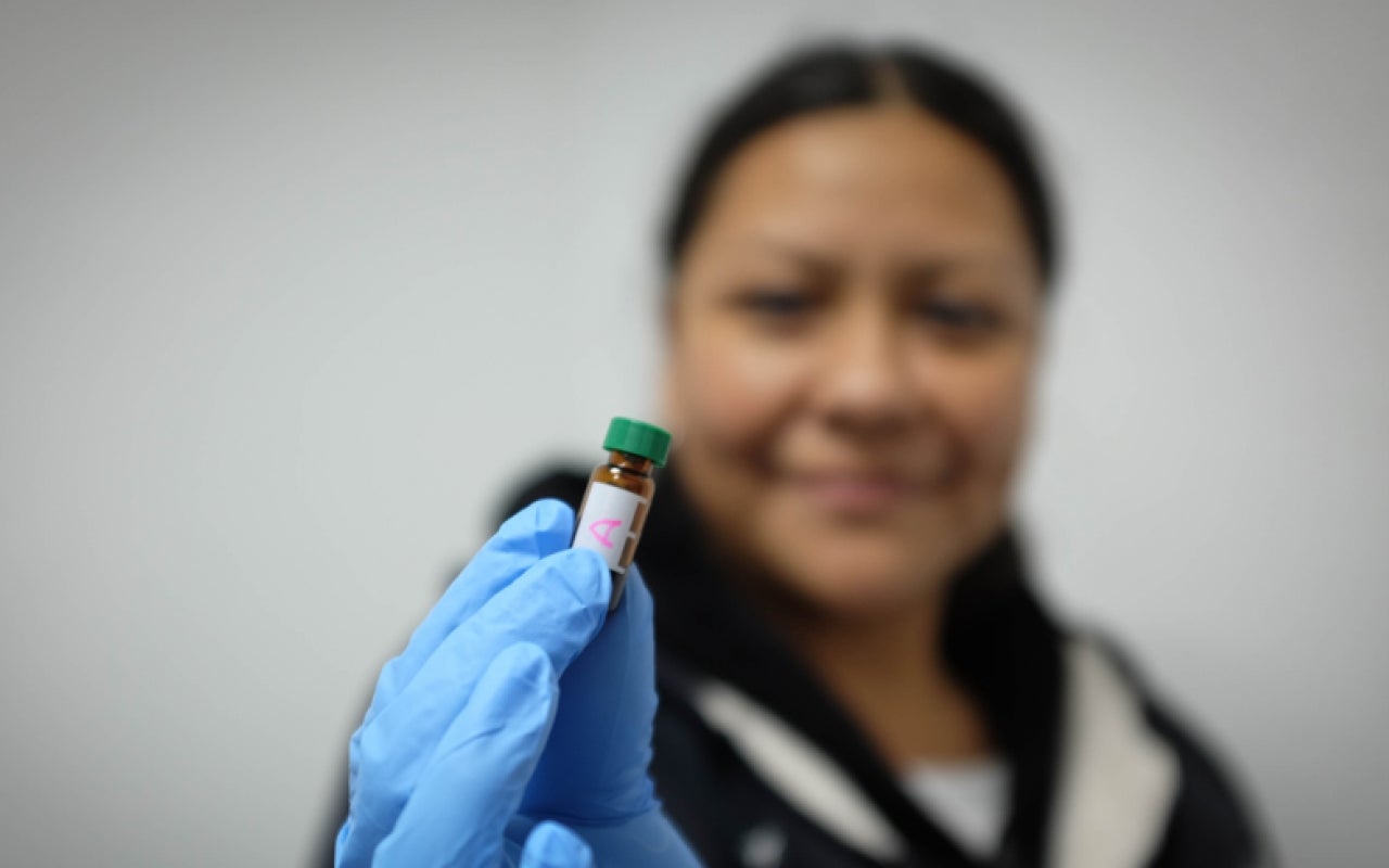 Woman holds up a small vial for the camera
