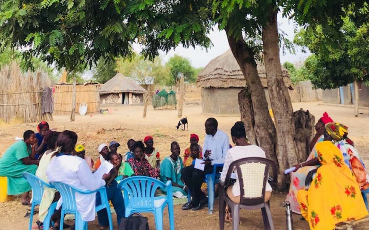 Women gathering under a tree near a village in South Sudan.