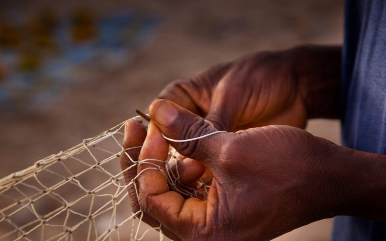 A person tying a fishing net in Sierra Leone