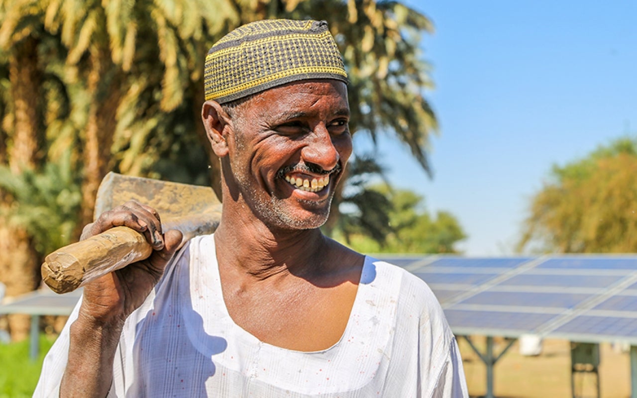 Sudanese man in front of solar panels