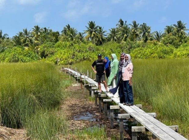 People standing on a wood walking bridge