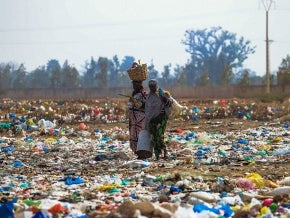 Women walking through a trash littered field in Dakar, Senegal