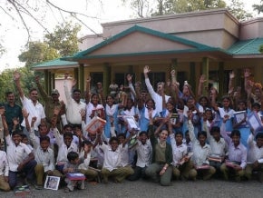 Students and teachers in a group photo with hands raised