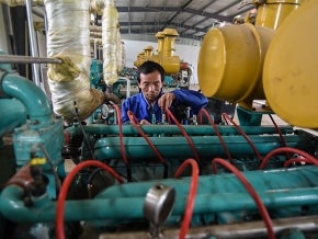 Chinese factory worker adjusting machinery