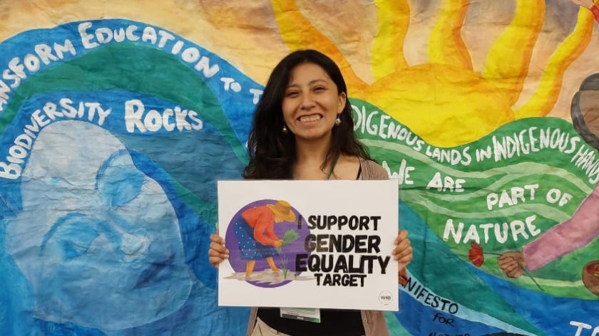 Woman holding sign behind colorful background