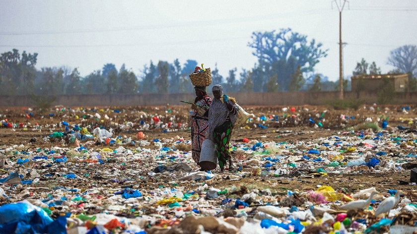 Women walking through a trash littered field in Dakar, Senegal