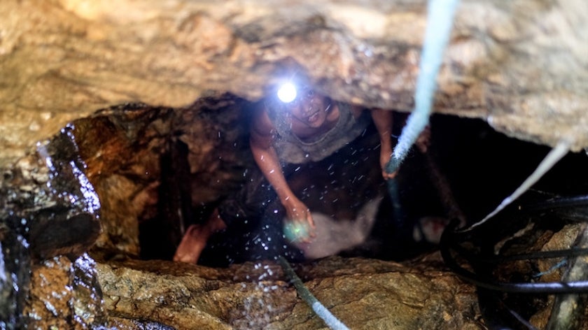 Small-scale gold miner inside a mining site looking up at camera