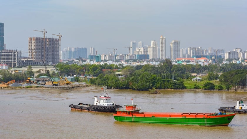 Ho Chi Minh City scene with river in foreground and various construction on high-rise buildings in background