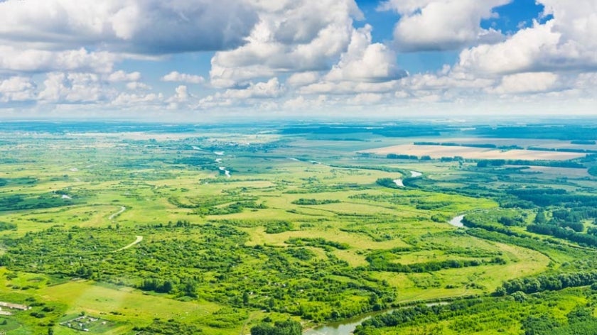 Aerial view of green landscape with cloudy skies above