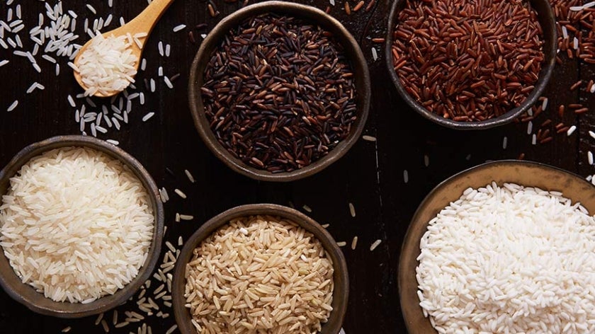 Different types of rice in bowls on a rustic table.
