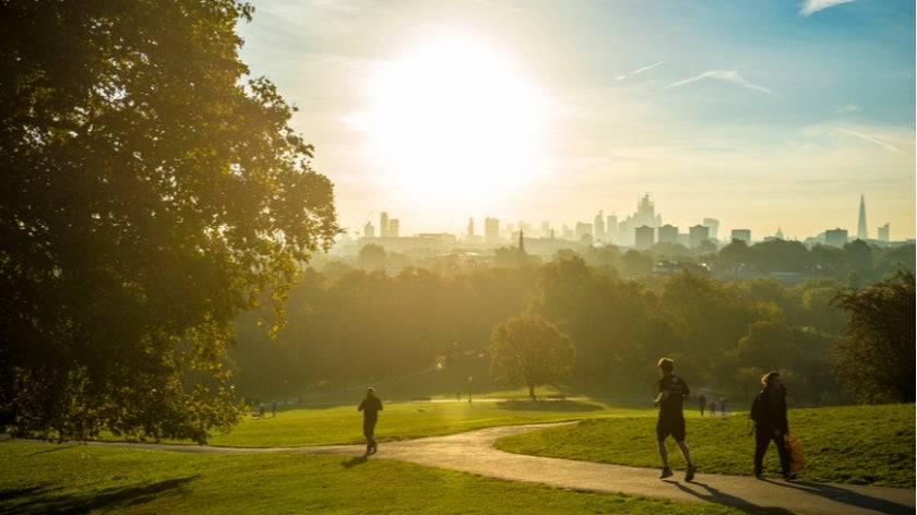 Joggers run through a park near London at sunrise