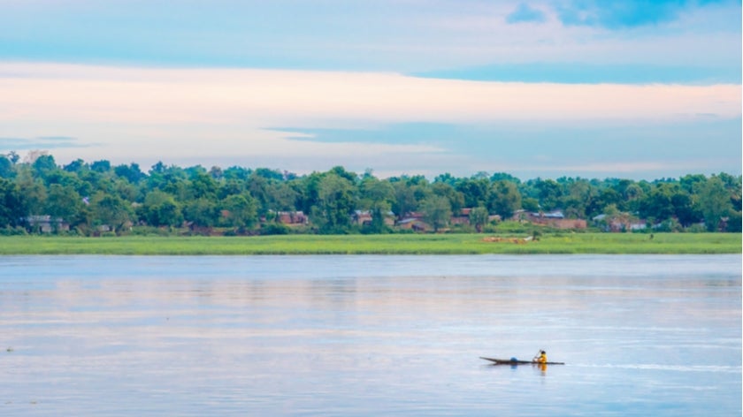 African fisherman rowing boat on Ubangi River, fishing in Bangui capital of Central African Republic. Traditional wooden boat made by African villagers
