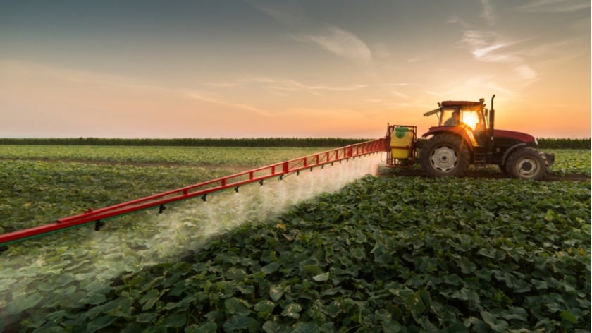 Tractor spraying pesticides on vegetable field with sprayer at spring. Photo: Fotokostic/Shutterstock.