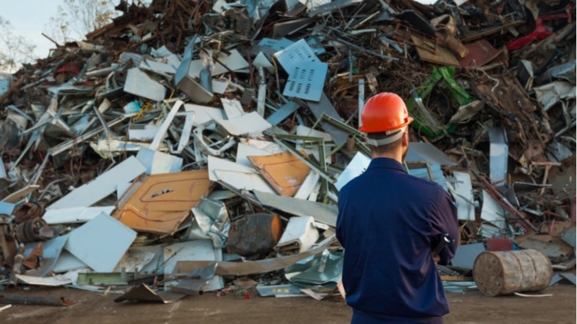 Man looking at piles of rubbish at a landfill. Photo: Comaniciu Dan/Shutterstock.